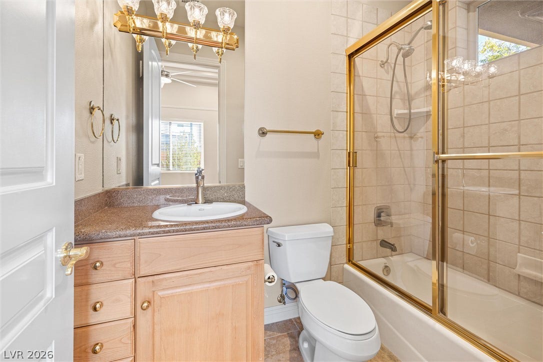 1517 Marbella Ridge Court, Las Vegas, NV 89117 Tiled walls and a gold-framed glass tub enclosure highlight this functional bathroom.