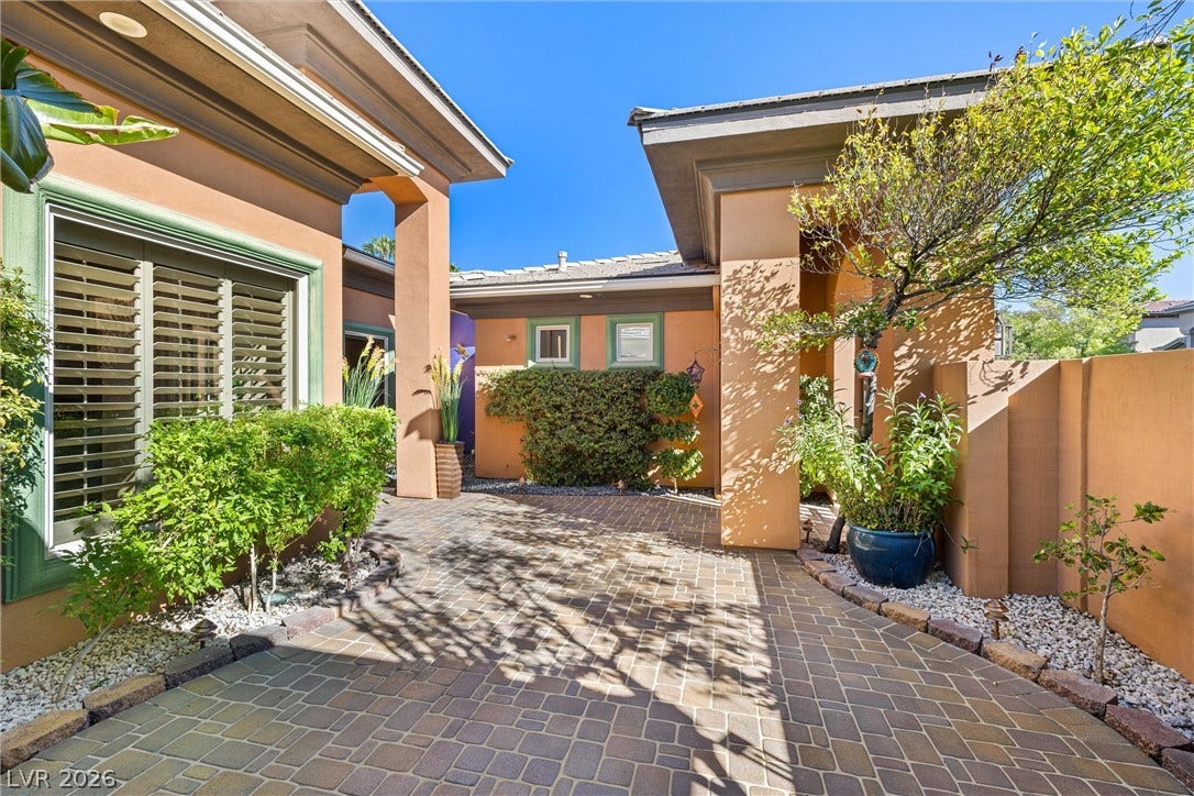 1517 Marbella Ridge Court, Las Vegas, NV 89117 An inviting stone-paved entry courtyard welcomes visitors with manicured plantings under desert skies.