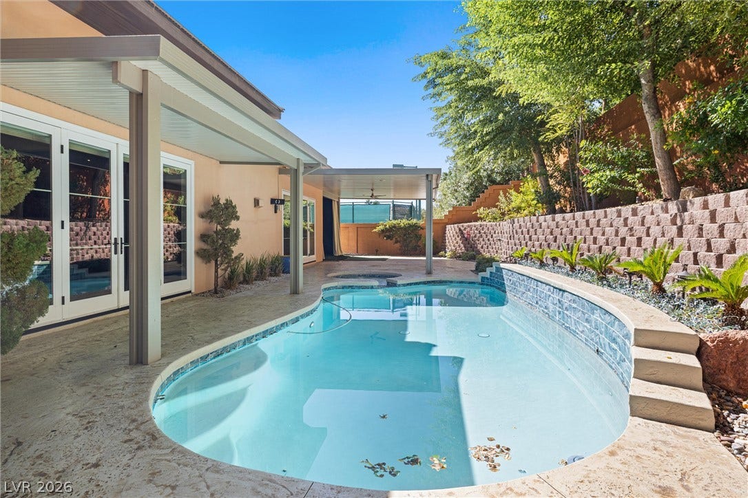 1517 Marbella Ridge Court, Las Vegas, NV 89117 A sparkling swimming pool highlights this backyard oasis, framed by a concrete patio and lush trees.
