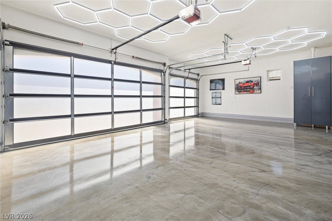 1517 Marbella Ridge Court, Las Vegas, NV 89117 Gleaming epoxy floors and geometric ceiling lighting elevate this modern multi-car garage space.