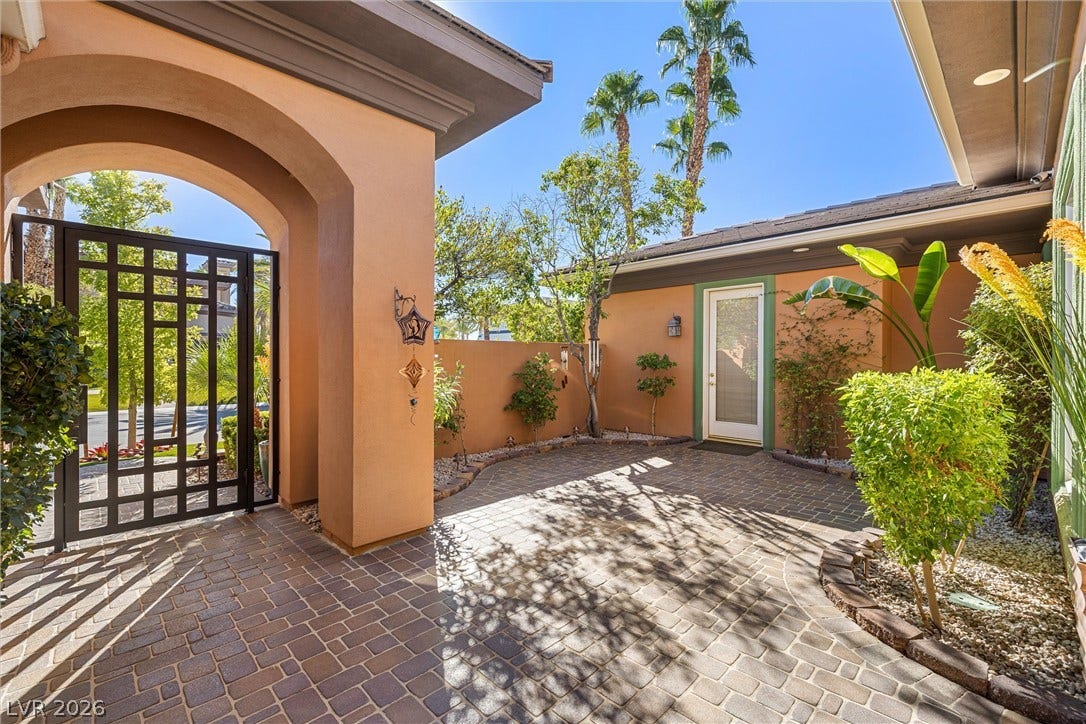 1517 Marbella Ridge Court, Las Vegas, NV 89117 A gated entry archway leads into a private paved courtyard surrounded by warm stucco walls.