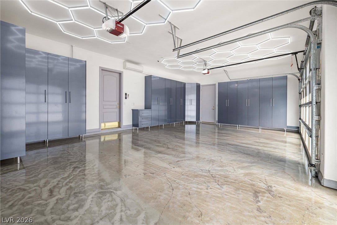 1517 Marbella Ridge Court, Las Vegas, NV 89117 Gleaming epoxy floors and extensive custom cabinetry define this modern multi-car garage space.