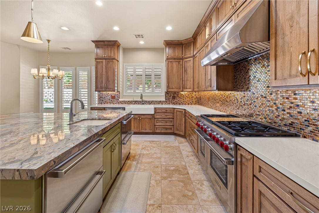1517 Marbella Ridge Court, Las Vegas, NV 89117 Rich wood cabinetry paired with stone countertops and tile flooring defines this chef-ready kitchen.