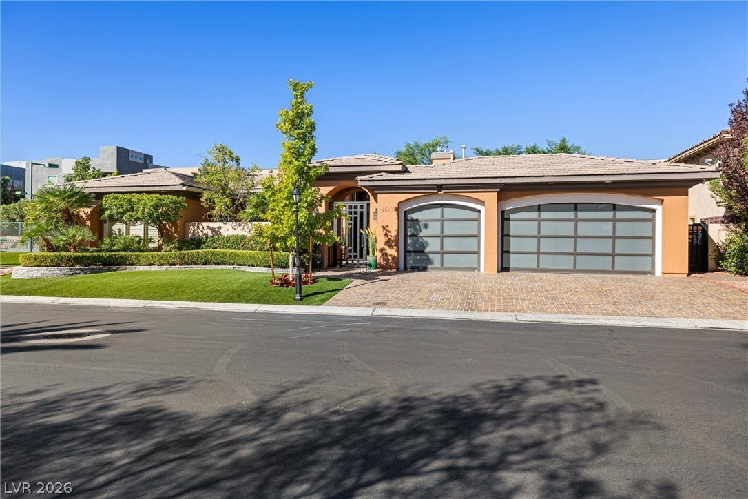 1517 Marbella Ridge Court, Las Vegas, NV 89117 Manicured landscaping and a paved driveway frame this elegant single-story facade with modern garage doors.