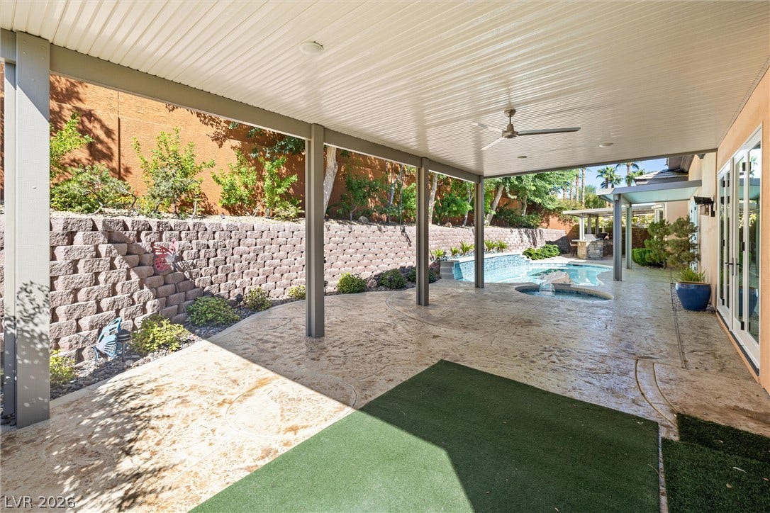 1517 Marbella Ridge Court, Las Vegas, NV 89117 An expansive covered patio overlooks a private pool and manicured hillside landscaping.