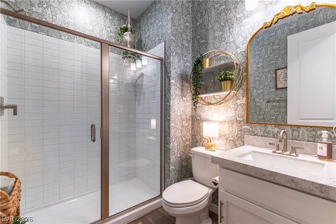 10583 Valletta Avenue, Las Vegas, NV 89166 Elegant patterned wallpaper and a glass-enclosed walk-in shower elevate this updated bathroom.