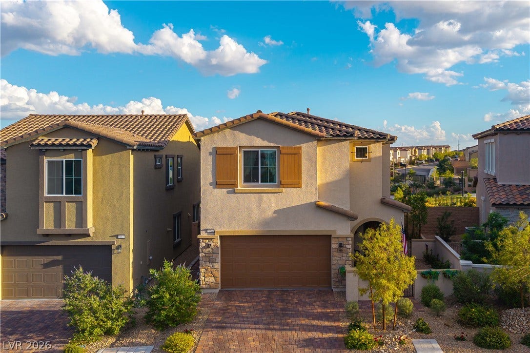 10583 Valletta Avenue, Las Vegas, NV 89166 A classic Spanish-inspired facade features decorative shutters, textured stucco, and a brick paver driveway.