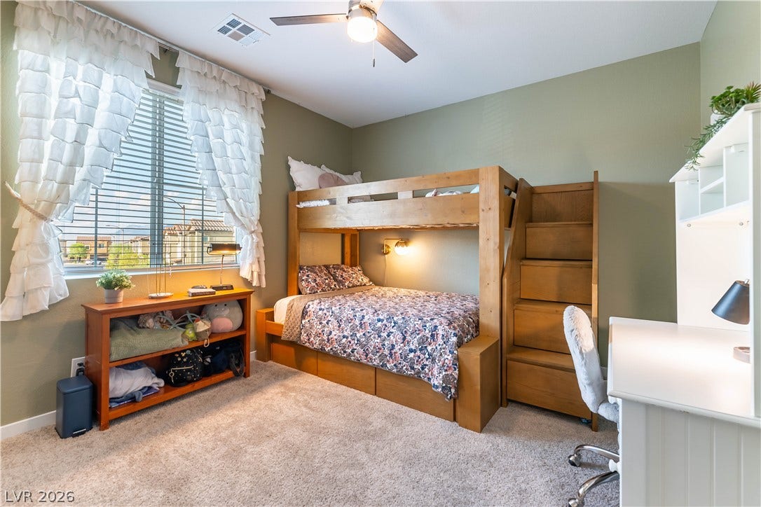 10583 Valletta Avenue, Las Vegas, NV 89166 A spacious secondary bedroom features comfortable carpeted flooring and large windows inviting natural light.