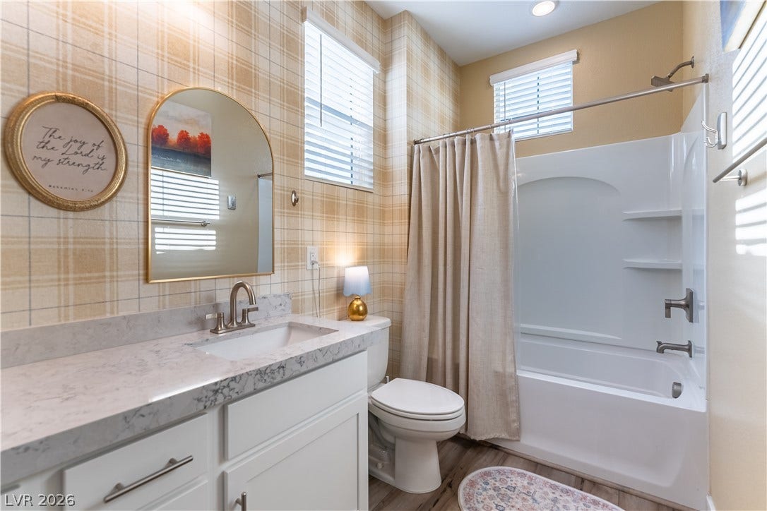10583 Valletta Avenue, Las Vegas, NV 89166 Plaid wallpaper complements a clean white vanity and integrated shower assembly in this cozy bathroom.