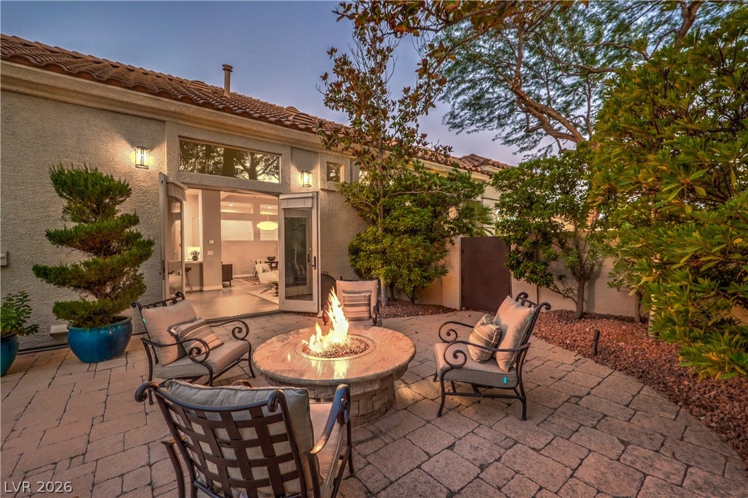 A private stone courtyard features a built-in fire pit surrounded by mature landscaping.