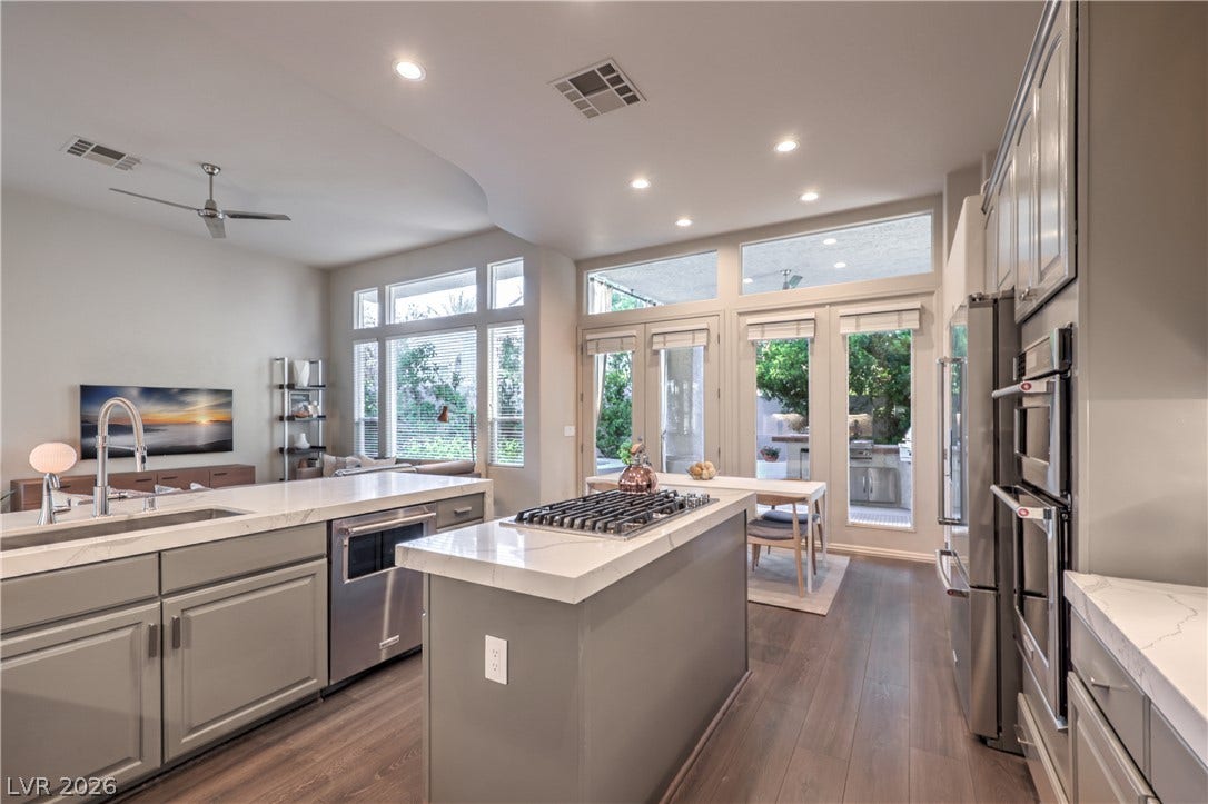 Rich hardwood flooring complements the stone countertops and seamless transitions in this open layout.