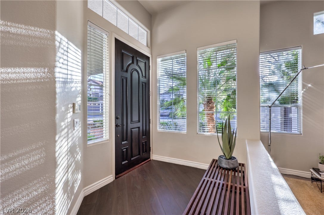 High ceilings and tall windows illuminate a welcoming entryway featuring dark wood floors.
