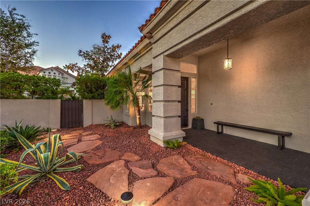 Welcoming front porch leads to a private courtyard lined with flagstone pathways and desert landscaping.
