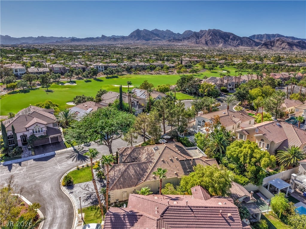 Dramatic mountain vistas rise above a manicured golf course and surrounding neighborhood homes.