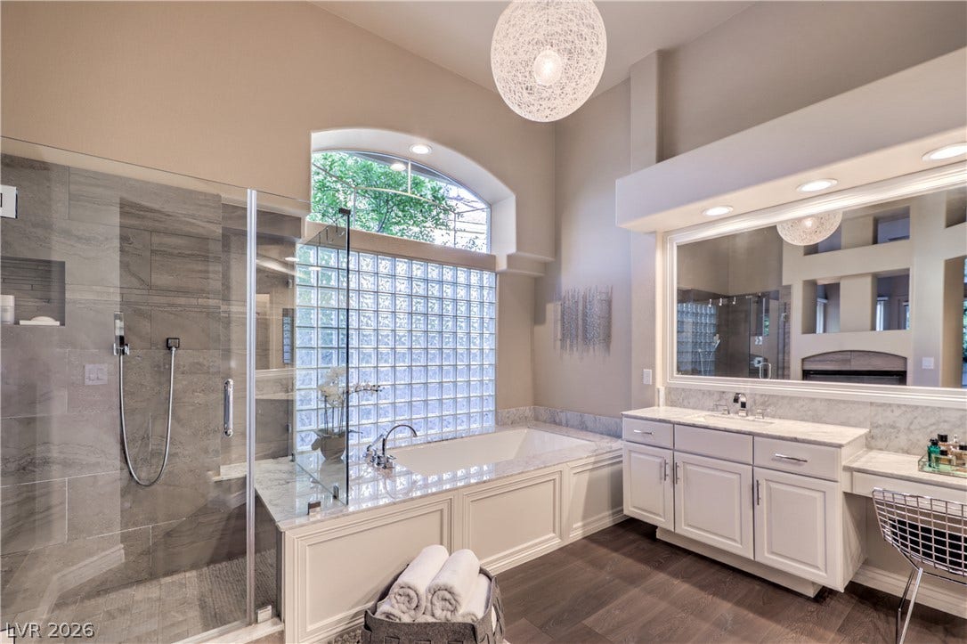 High ceilings, stone tiling, and a deep soaking tub define this elegant primary bath.