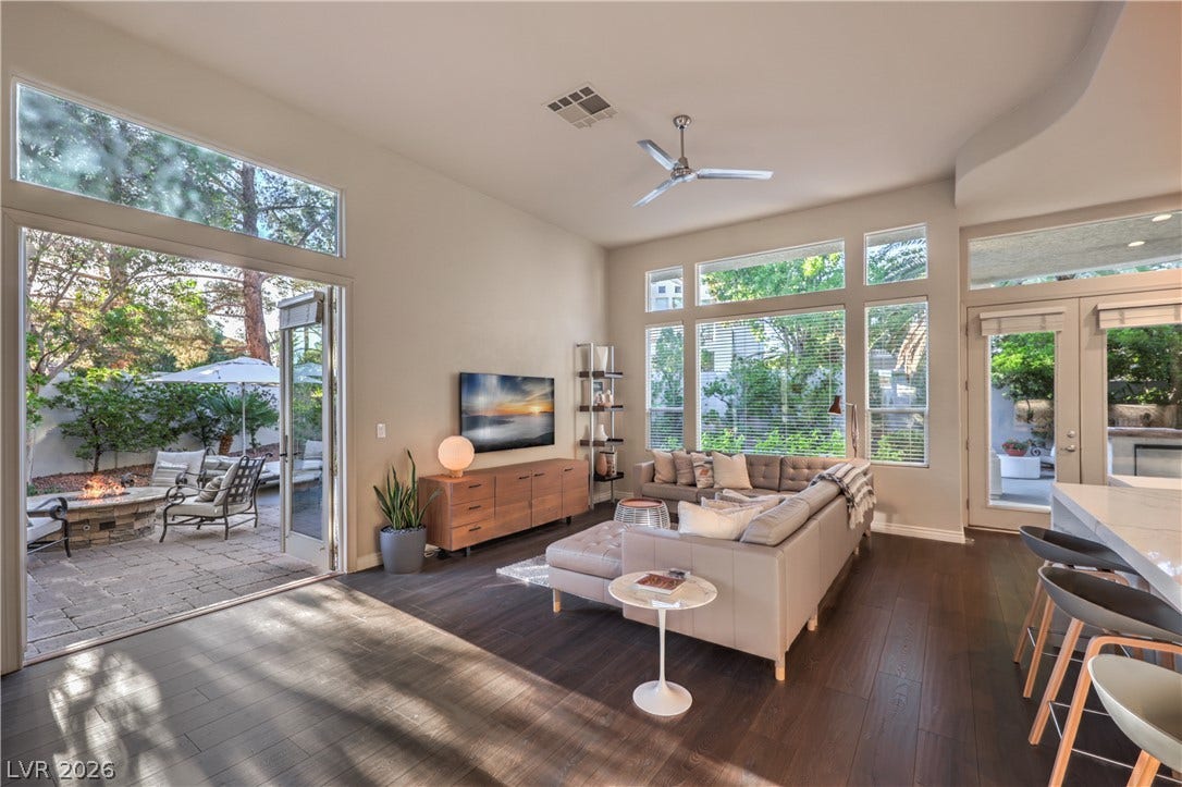 Gleaming wood floors and towering windows frame views of the private backyard patio.