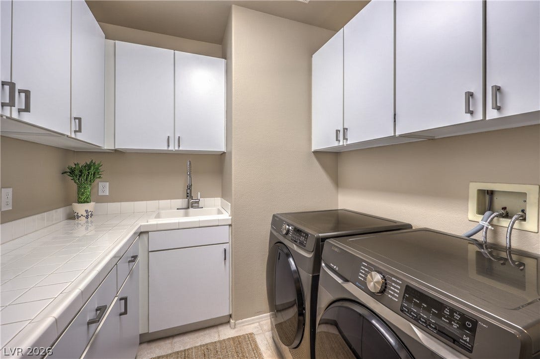 Ample white cabinetry and tiled countertops organize this highly functional utility space.