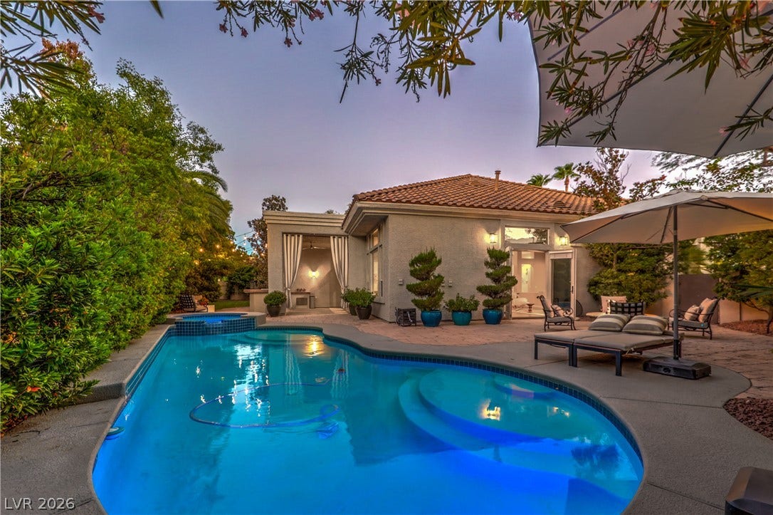 An inviting backyard oasis features a curved swimming pool integrated with a stone patio.