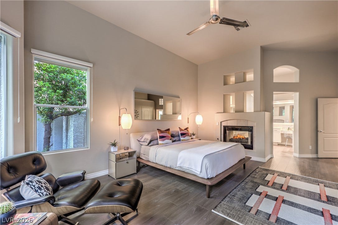 High ceilings and a cozy fireplace define this comfortable primary bedroom suite.
