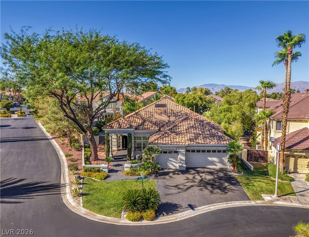 A classic tile roof and manicured green lawns define this elegant suburban corner-lot home.