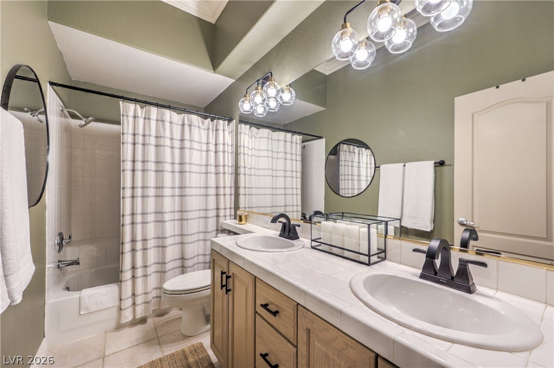 Double vanities and a tiled tub shower combination define this functional bathroom layout.