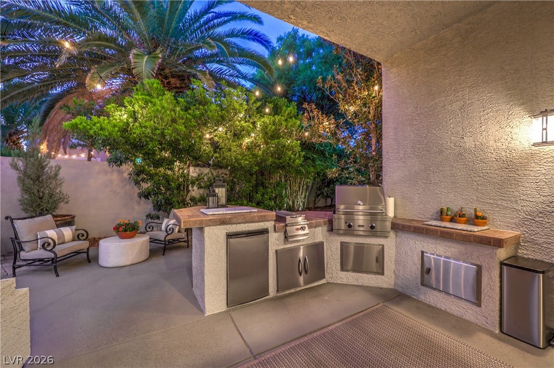 A fully equipped outdoor kitchen stands ready for open-air dining under a sheltered patio.