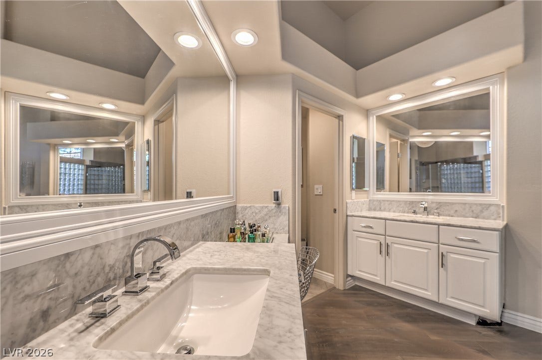 Elegant marble countertops and rich wood flooring anchor this beautifully designed washroom space.