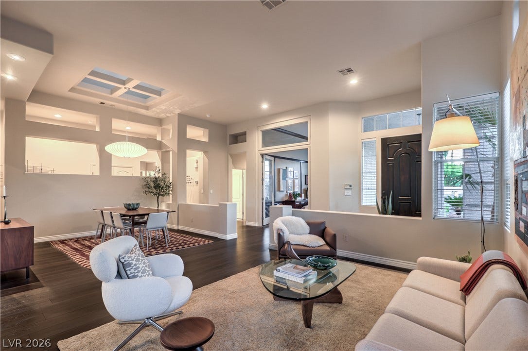 Rich dark wood floors anchor an airy, open-concept living area with soaring ceilings and abundant windows.