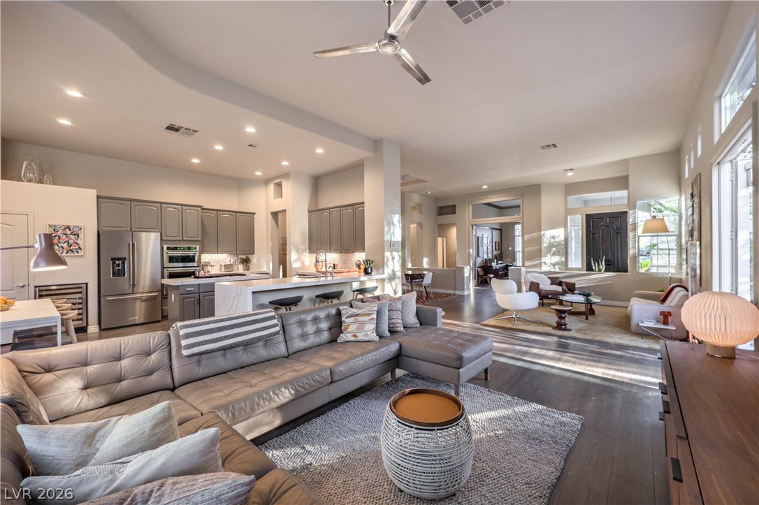 An open floor plan connects the kitchen, dining, and living spaces over rich wood floors.