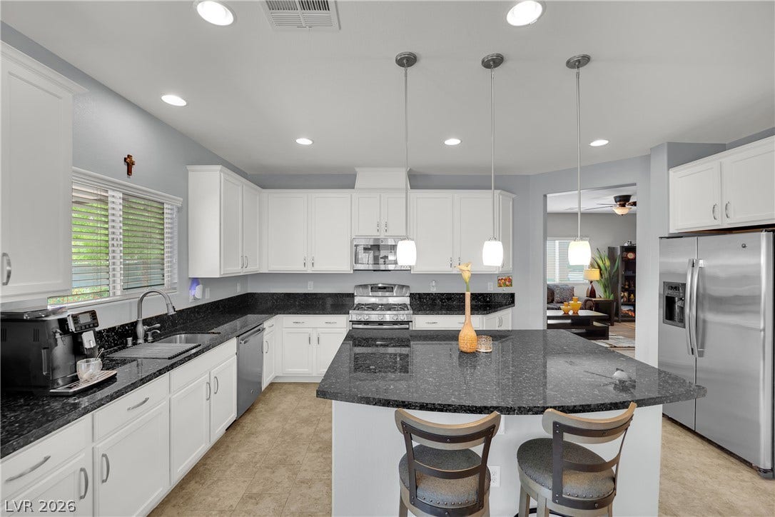 1421 Lamance Court, North Las Vegas, NV 89031 Gleaming stone countertops and a spacious central island anchor this light-filled culinary space.