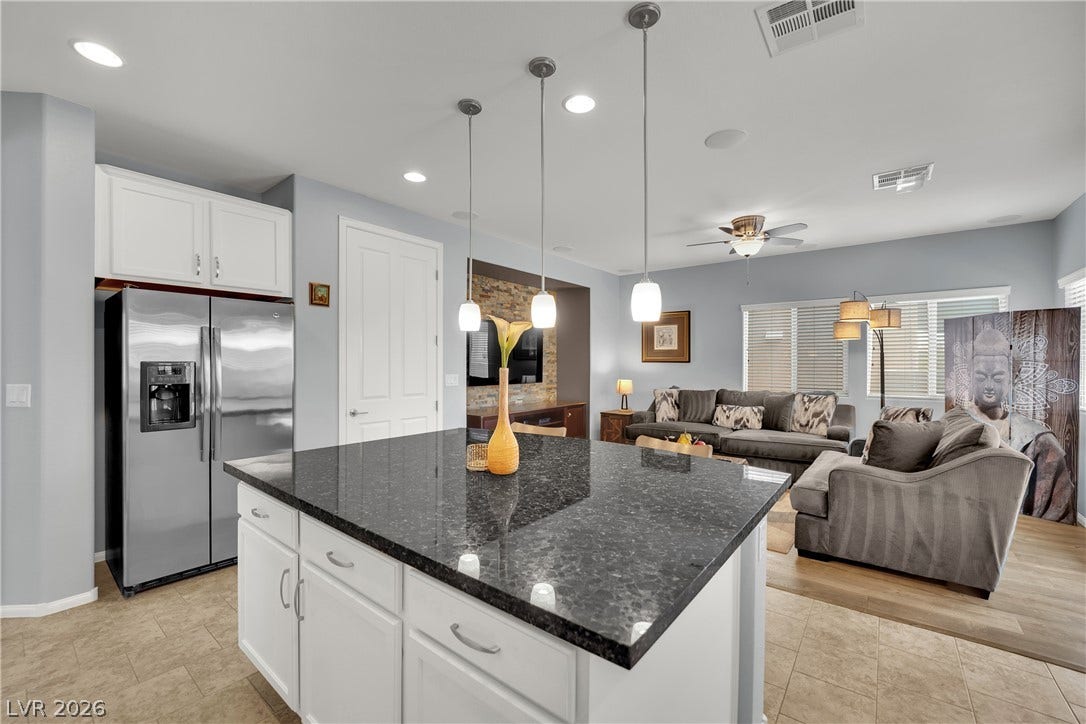 1421 Lamance Court, North Las Vegas, NV 89031 Granite countertops and white cabinetry anchor an open-concept layout connecting to the living space.