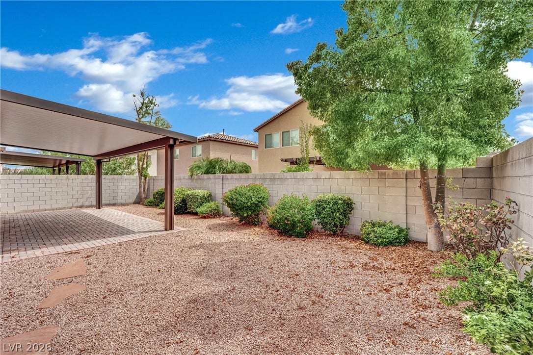 1421 Lamance Court, North Las Vegas, NV 89031 A spacious backyard features low-maintenance gravel landscaping, mature trees, and a covered patio structure.