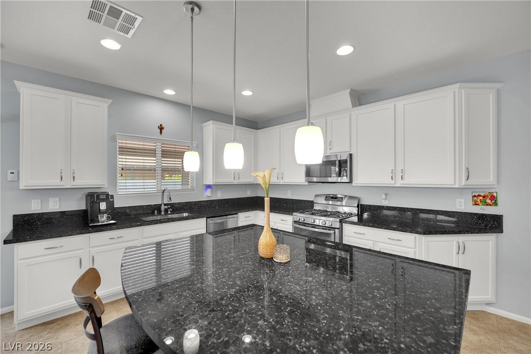 1421 Lamance Court, North Las Vegas, NV 89031 Gleaming stone countertops and a spacious central island anchor this modern open kitchen.