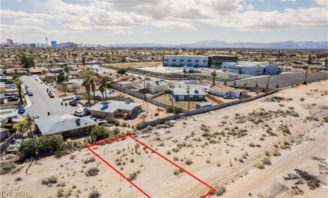 An aerial perspective reveals a vacant desert lot outlined near residential neighborhoods.