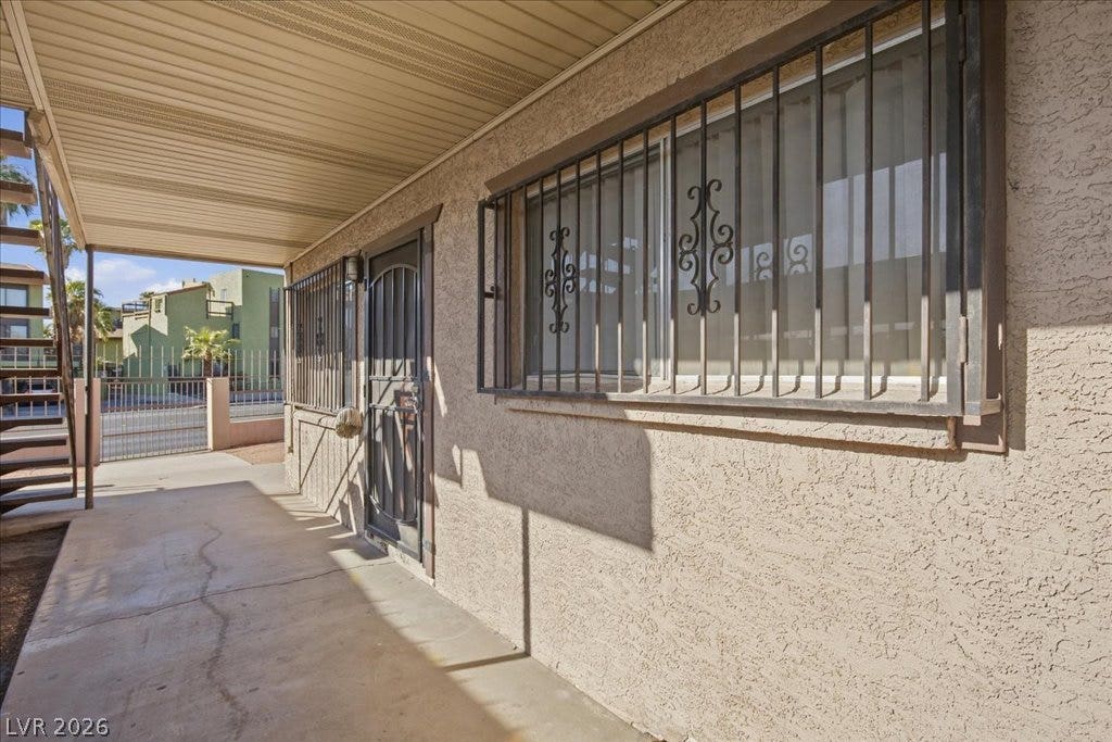 3726 Hazelwood Street, #14, Las Vegas, NV 89119 A covered concrete walkway runs alongside the textured exterior wall to the entrance.