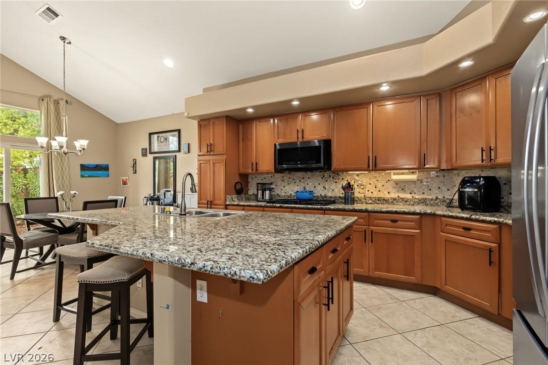 7021 Albatross Attic Street, North Las Vegas, NV 89084 Gleaming granite countertops and rich wood cabinetry define this open kitchen design.
