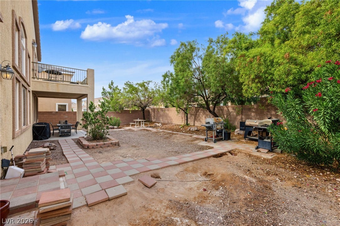 7021 Albatross Attic Street, North Las Vegas, NV 89084 Mature trees line the perimeter of this fenced back yard with paved patio spaces.