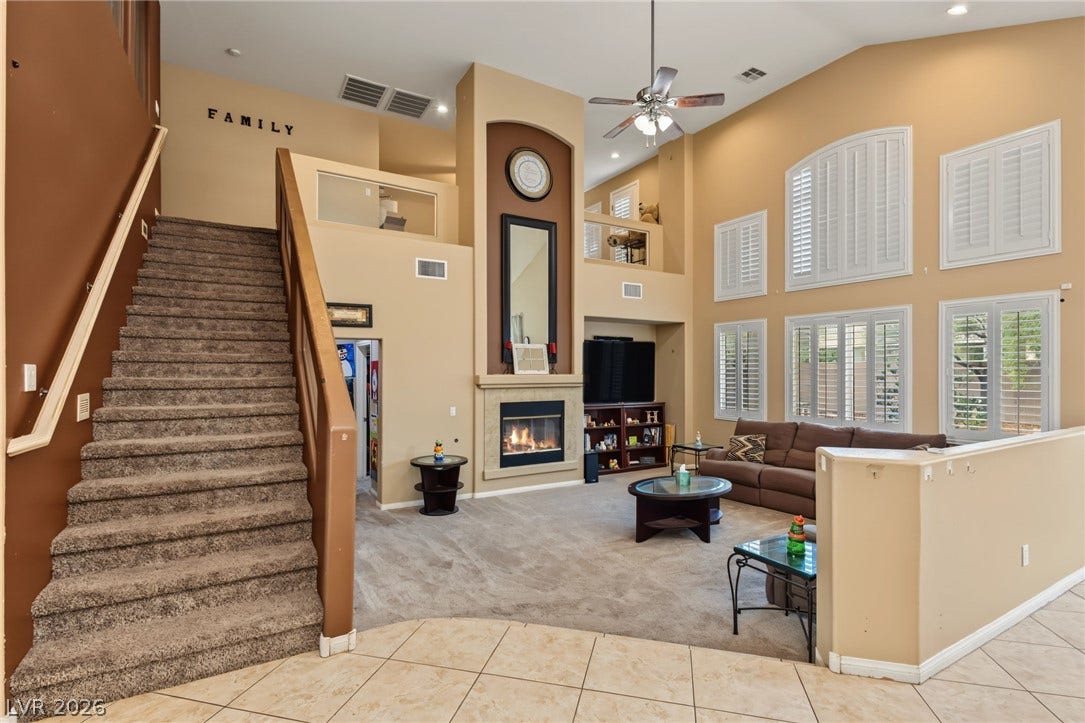 7021 Albatross Attic Street, North Las Vegas, NV 89084 Soaring ceilings and a cozy fireplace anchor this open two-story living area.