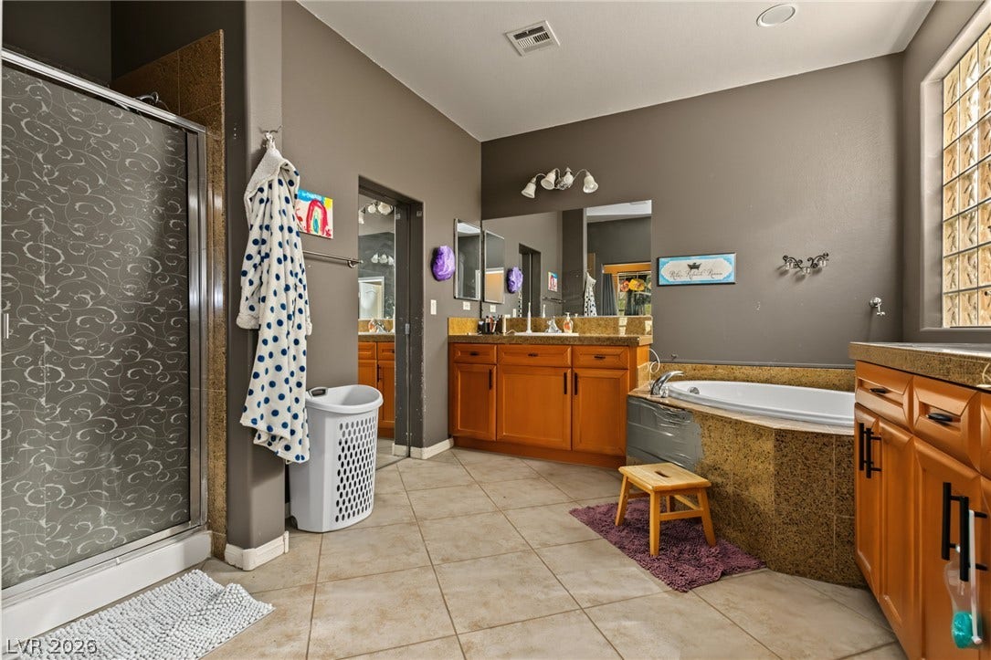 7021 Albatross Attic Street, North Las Vegas, NV 89084 Ceramic tile floors and a built-in soaking tub anchor this spacious primary bath layout.