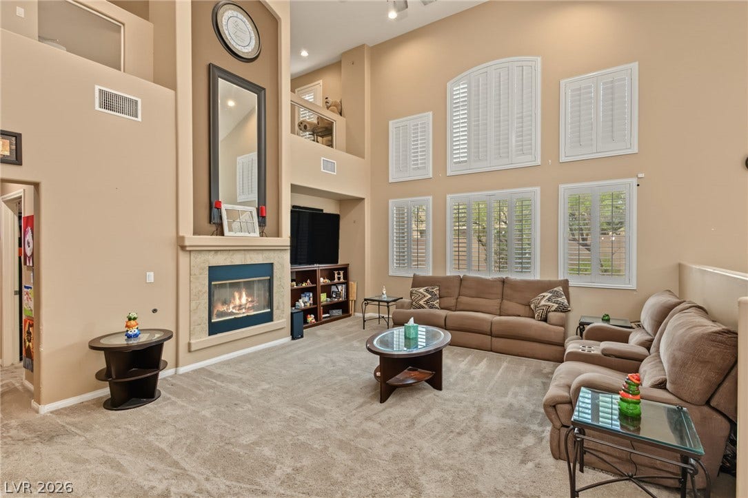 7021 Albatross Attic Street, North Las Vegas, NV 89084 Towering ceilings and a grand fireplace frame this light-filled main living space.
