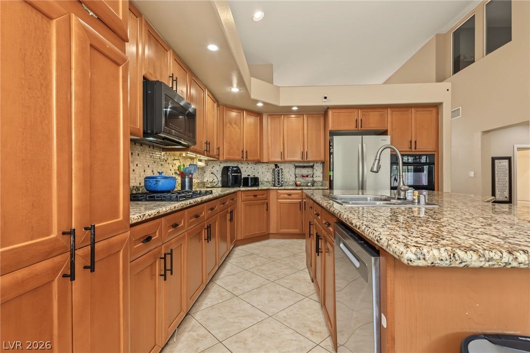 7021 Albatross Attic Street, North Las Vegas, NV 89084 Rich wood cabinetry paired with stone countertops defines this well-appointed gourmet kitchen space.