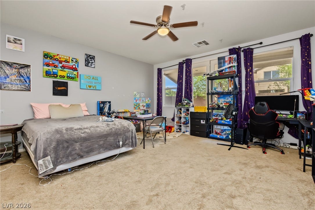 7021 Albatross Attic Street, North Las Vegas, NV 89084 A spacious bedroom features neutral walls, wall-to-wall carpeting, and multiple large windows overlooking the outdoors.
