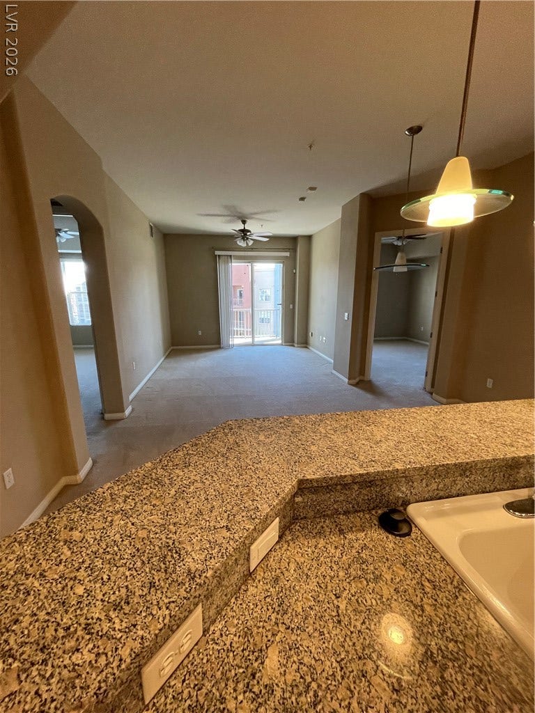 32 E Serene Avenue, #407, Las Vegas, NV 89123 Granite countertops frame the breakfast bar looking out to the carpeted living area.
