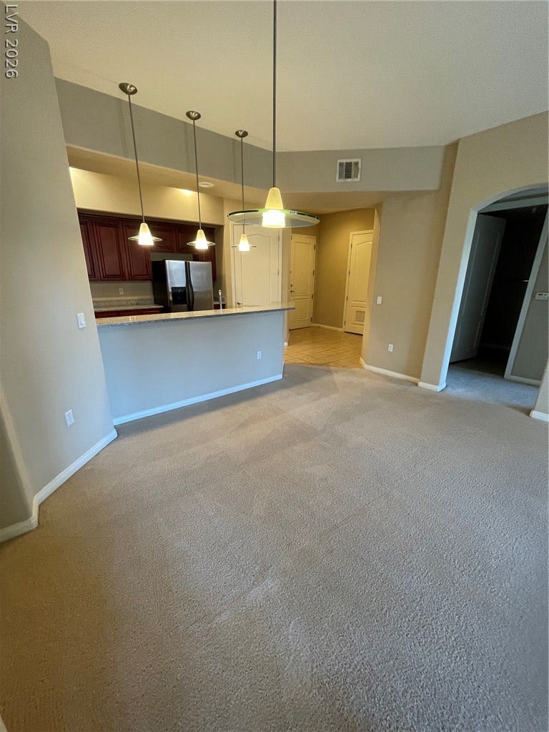 32 E Serene Avenue, #407, Las Vegas, NV 89123 A spacious carpeted living area connects seamlessly to an open kitchen with high ceilings.