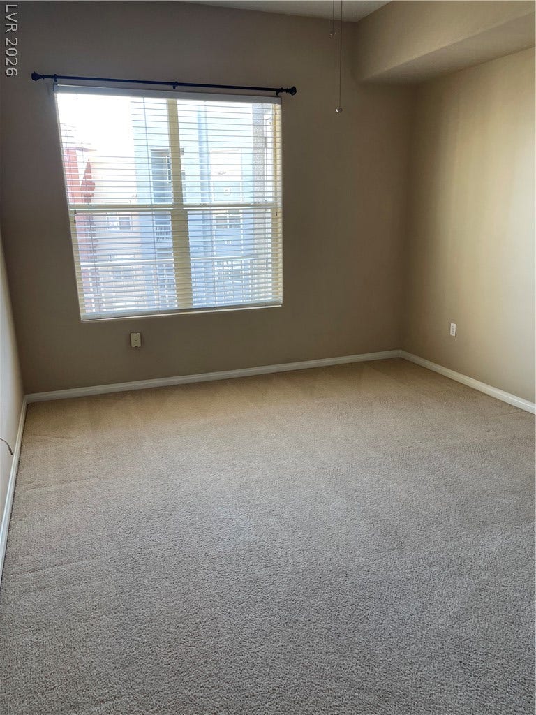 32 E Serene Avenue, #407, Las Vegas, NV 89123 A spacious room features plush carpeting and a large window inviting abundant natural light.