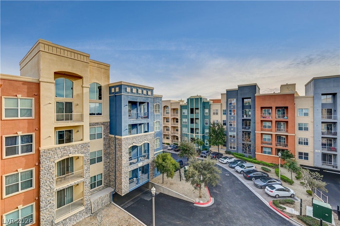 32 E Serene Avenue, #407, Las Vegas, NV 89123 Multi-story residential buildings surround a paved central parking area with young trees.