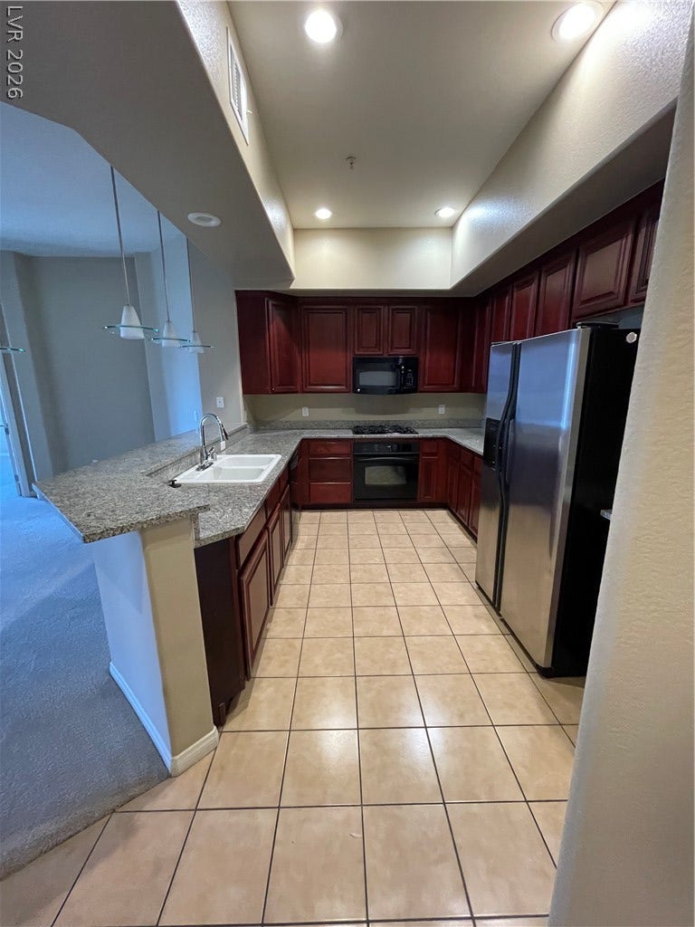 32 E Serene Avenue, #407, Las Vegas, NV 89123 Rich wood cabinetry and stone countertops define this functional kitchen workspace.