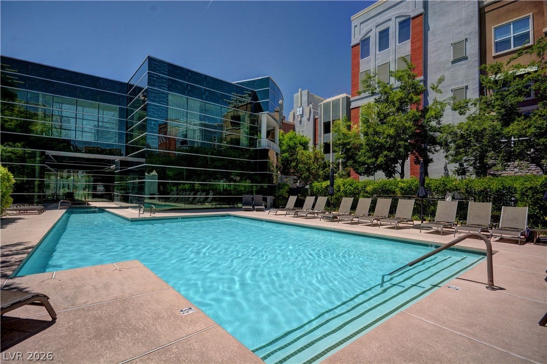 32 E Serene Avenue, #407, Las Vegas, NV 89123 Modern mid-rise buildings frame a pristine outdoor swimming pool surrounded by spacious sunbathing decks.