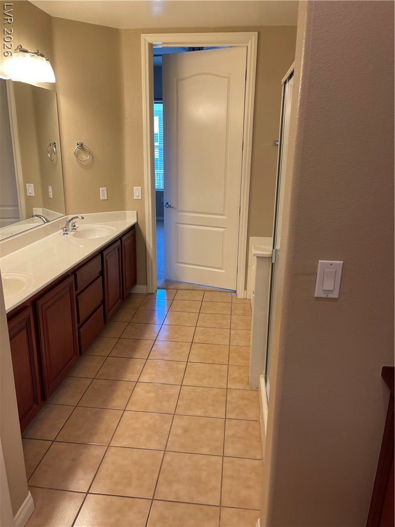32 E Serene Avenue, #407, Las Vegas, NV 89123 Clean tile flooring and classic wood cabinetry define this functional bathroom space.