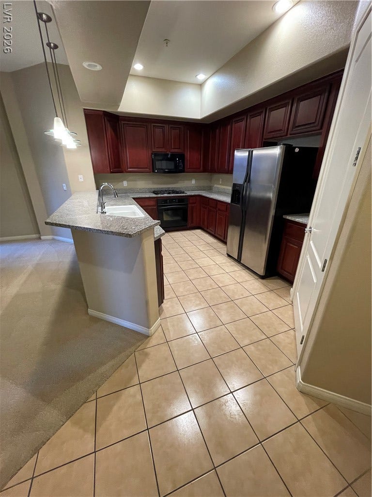 32 E Serene Avenue, #407, Las Vegas, NV 89123 Rich wood cabinets and gleaming tile floors define this functional kitchen layout.